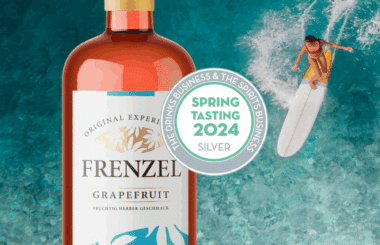 Likör FRENZEL Grapefruit mit SILBER-Medaille bei The Spirits Business Spring Tasting 2024 – Flasche vor türkisfarbenem Wasser mit Surfer