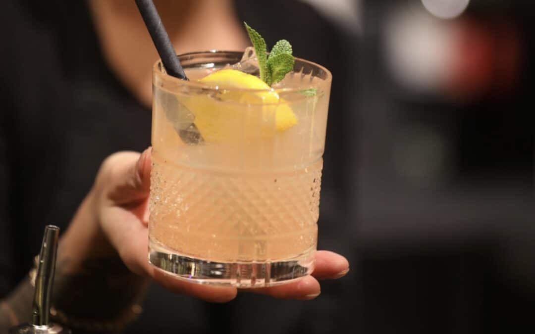 Ein erfrischender Cocktail mit FRENZEL Grapefruit Likör, garniert mit Zitrone, Minze und Eiswürfeln in einem edlen Glas.