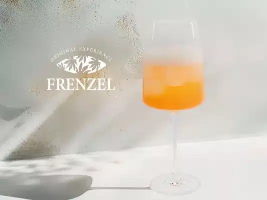 FRENZEL Spritz mit Grapefruitlikör in elegantem Weinglas vor heller Wand im HERZSTÜCK Hamburg
