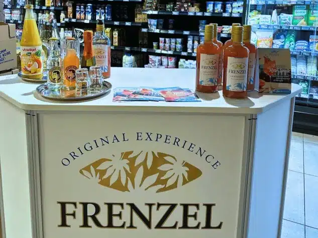 Verkostungsstand von FRENZEL Grapefruit im EDEKA Thiel in Velbert-Neviges mit Likörflaschen, Gläsern und Werbematerialien im Frischebereich des Marktes.